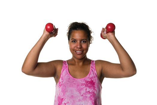 Mixed raced young woman  in pink shirt exercising with red 2 kg weights dumbbells isolated in white