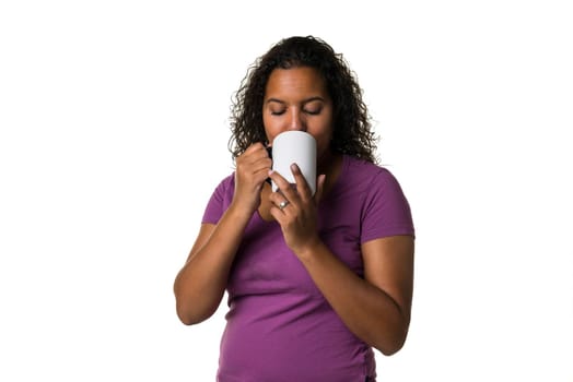 Young mixed race woman in purple shirt drinking a hot liquid from a black and white cup isolated with a white background