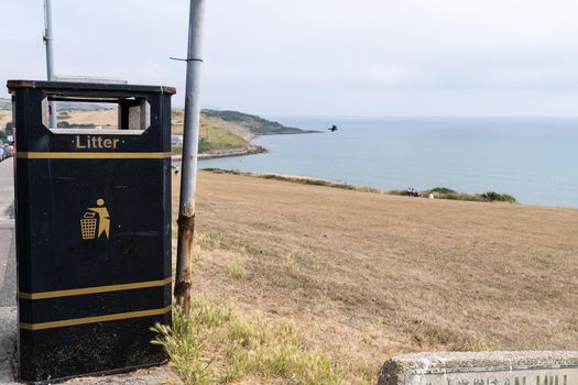 A Black and yellow litter bin or garbage can at a coastal area in Great Brittain England south coast