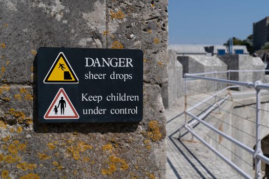 Danger sudden drop sign yellow warning triangle with symbol of man falling from a cliff edge and keep children under control sign on rampage