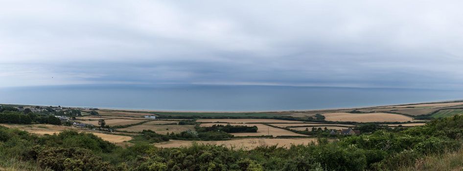 A South Dorset coastline near Weymouth, England. With meadows, clouds and deep blue sea. Panorama and banner