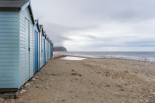 Blue beach holiday house by the English Channel on Jurassic coast in Charmouth, Dorset, United Kingdom, UK. British summer holidays, hilly countryside, beach summer destination.