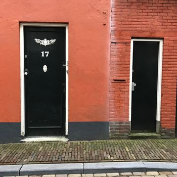 Green frontdoors in a terracotta painted wall in the city with a pavement