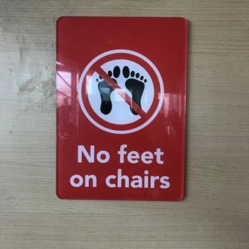 a Sign forbidden to out your feet on the chairs in English