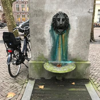 an Ancient Waterfountain or pump shaped like a lion with a bike parked next to it in the city of Utrecht, The Netherlands