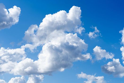 Skyscape with cumulus clouds in white and grey and a clear deep blue sky in the summer