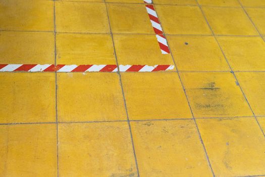 A yellow tiled floor with red and white tape