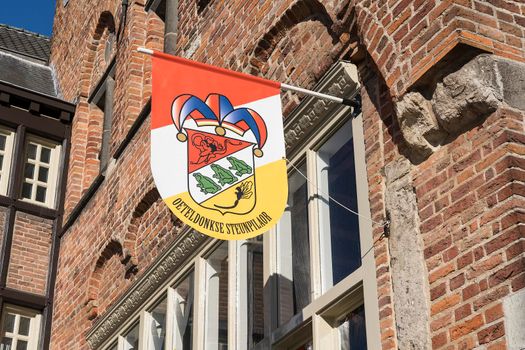 A Dutch flag, in red, white and yellow, of traditional festival named Carnaval, like Mardi Gras, in 's-Hertogenbosch, Oeteldonk hanging on a building