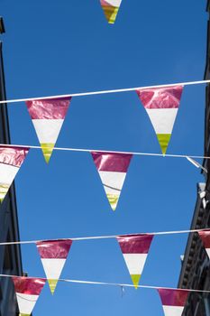 A Dutch triangular flags on a ribbon, in red, white and yellow, of traditional festival named Carnaval, like Mardi Gras, in 's-Hertogenbosch, Oeteldonk with a blue sky