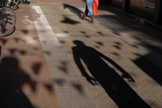 The Shadow of a man following a woman on the pavement looking suspicious or scary, concept for an assault or attack