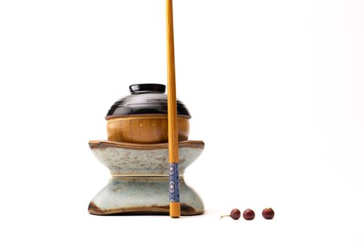 A still life of a japanese figure built from cups and a chopstick isolated on a white background