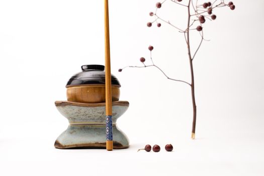 A still life of a japanese figure built from cups and a chopstick isolated on a white background