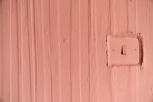a Full frame of a terracotta painted old wall with wallpaper and vertical structured lines and a licght switch