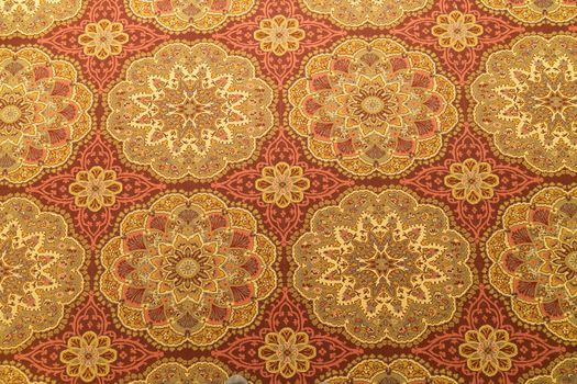 a Close up of a detail or a fug or tapestry on the floor in yellow and orange and gold with circular patterns seen from above