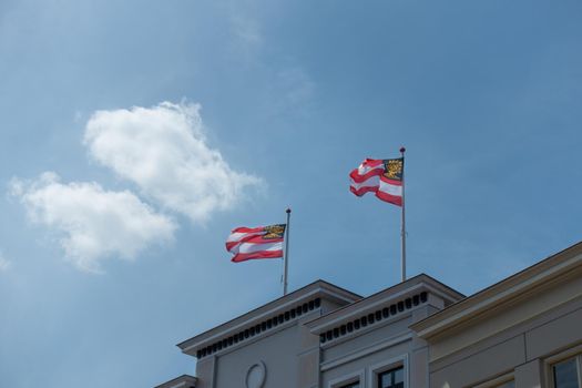 Two flags of the Duch city of 's-Hertogenbosch or Den Bosch, capital of the province Noord Brabant against a clear blue sky with clouds