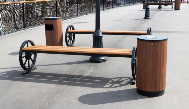 There are beautiful brown benches and urns on the pedestrian bridge.