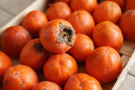 Ripe orange persimmons in a drawer. The texture of the background is from persimmon fruit. High quality photo
