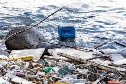 Plastic container floating on a beach side and other plastic garbage and trashes