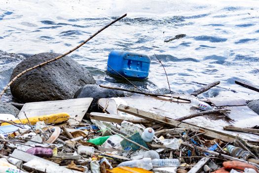 Plastic container floating on a beach side and other plastic garbage and trashes