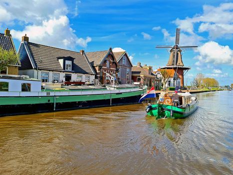 Cruising on a canal in the countryside from the Netherlands with a traditional windmill