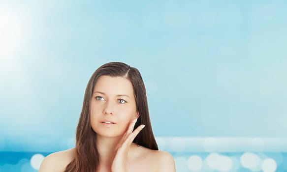 Skincare and sun protection in summer. Portrait of a beautiful young suntanned woman, blue sea and sky on background, beauty, wellness and travel concept.