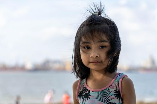 Pretty little asian girl in the beach with blurry background and colorful swimming suit.