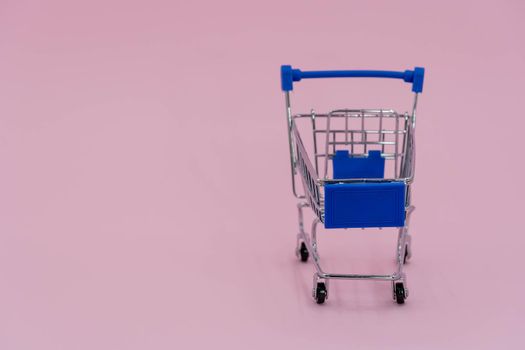 shopping cart isolated on pink background. Blue shopping cart online shopping concept
