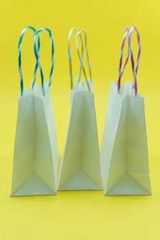 Colourful paper shopping bags isolated on Yellow Background. Closeup shot of white shopping bags