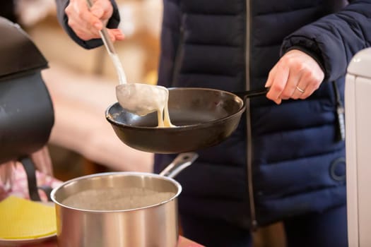 Pancakes are cooked on the street. Pour pancake dough into a pan. Maslenitsa.