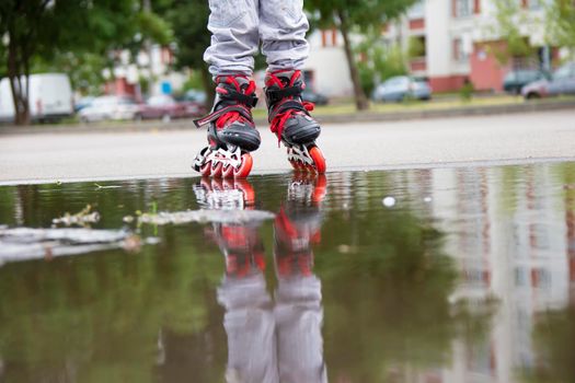 Roller skating. Legs in roller skates ride through a puddle.