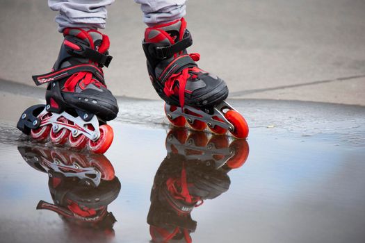 Roller skating. Legs in roller skates ride through a puddle.