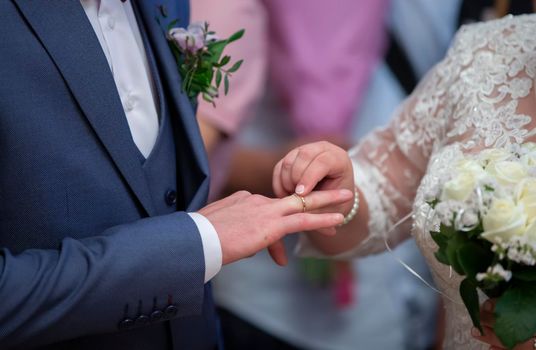 Wedding ceremony. Hand of the bride puts a ring on the finger of the groom. Wedding ring.