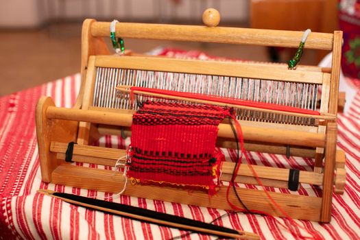 Spinning machine. An old wooden spinning wheel on a table with an embroidered shirt.