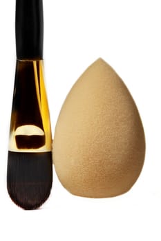 Cosmetic brush and face sponge vertically on a white background. Means for applying cosmetics.