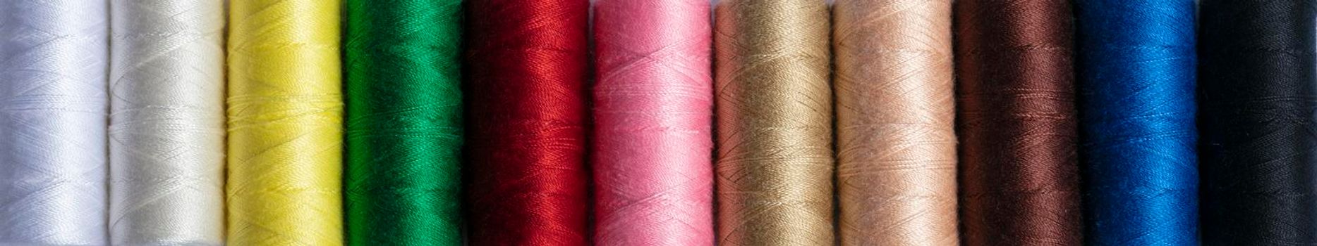 Colorful sewing threads in a row for a banner. The texture of multi-colored threads.