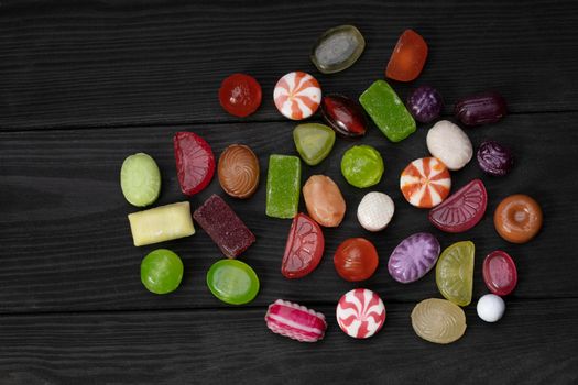Candies on a dark background. Multi-colored caramel on a wooden board. Sweets.