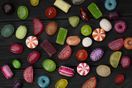 Candies on a dark background. Multi-colored caramel on a wooden board. Sweets.