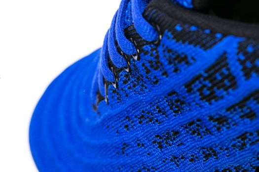 Part of a blue sneaker made of fabric with laces. A fragment of sports shoes.