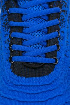 Part of a blue sneaker made of fabric with laces. A fragment of sports shoes.