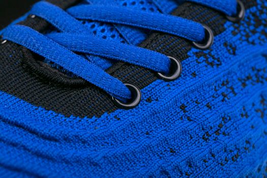 Part of a blue sneaker made of fabric with laces. A fragment of sports shoes.