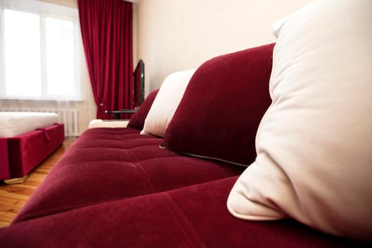 Part of a red sofa with white pillows in the living room.