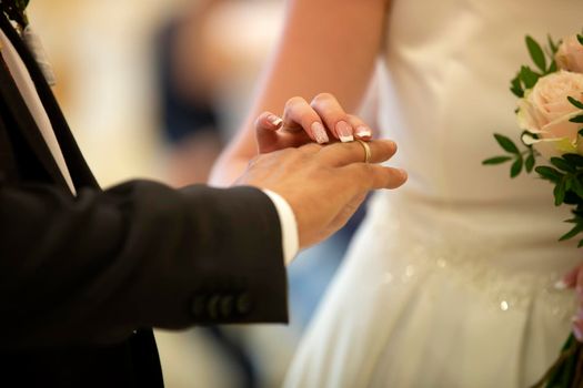 Wedding ceremony. Hand of the bride puts a ring on the finger of the groom. Wedding ring.