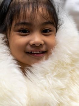 Pretty asian child wearing a white coat made of fur. Pretty asian model wearing white fur coat