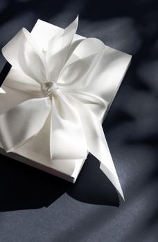 Anniversary celebration, shop sale promotion and luxe surprise concept - Luxury holiday white gift box with silk ribbon and bow on black background, luxe wedding or birthday present