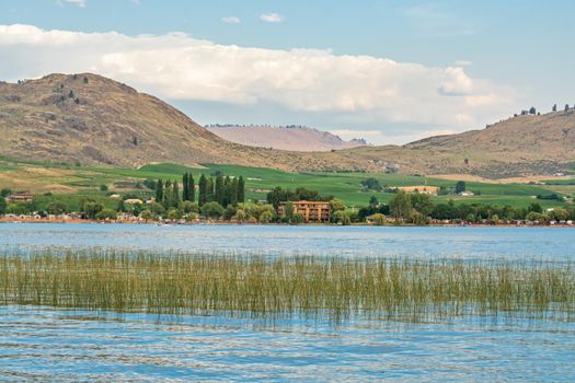 Warm summer evening on Osoyoos lake. Overview of farm lands and resorts on mountains and sky background