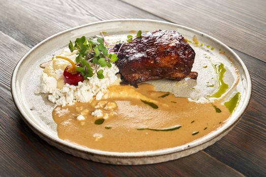 Close up view of juicy grilled beef steak served with mashed potato puree, cottage cheese, sauce and sprouts. Tasty dish presented on wooden table in restaurant. Cuisine concept.