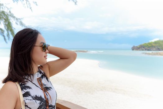 Beautiful woman tourist wearing sunglasse smiling looking at the nature landscape of the beach and the sea in summer sky on Tarutao island National Park, Satun, Thailand