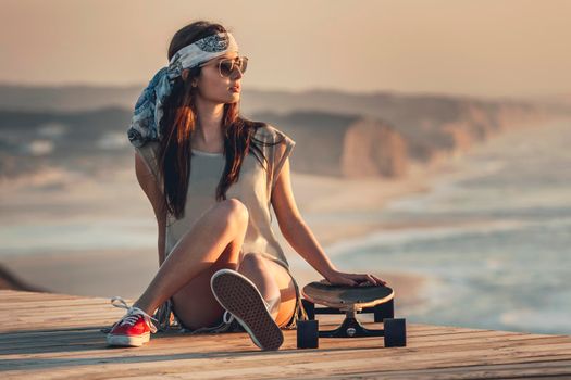 Beautiful fashion skater girl posing with  a skate board