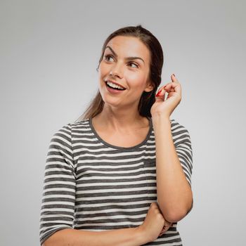 Portrait of a woman with a expression of having an idea. overa gray background