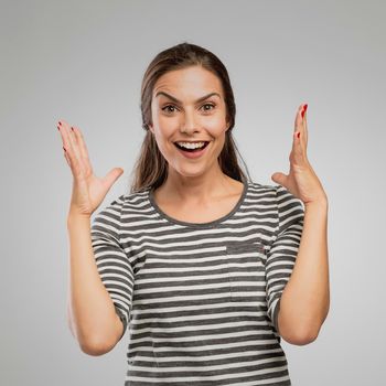 Portrait of a woman after receiving great news, over a gray background